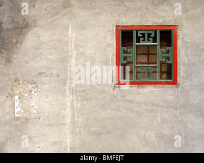 Tradizionalmente piccola piazza ornata finestra della ventola sul muro di casa in hutong a Pechino, Cina Foto Stock