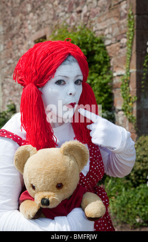 Donna Clown Rag Doll abiti fantasiosi. Un pauroso donna vestita con parrucca rosso e bianco faccia dipinta, a Muncaster Castle, Cumbria, England, Regno Unito Foto Stock