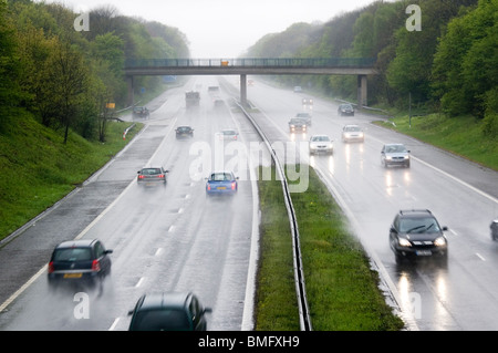 Le vetture che viaggiano a velocità in pioggia sulla autostrada M2 nel Kent, Inghilterra Foto Stock