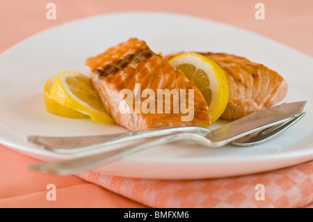 Filetto di salmone con le fette di limone servita su una piastra bianca Foto Stock