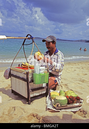 Un uomo preparare frutta per i clienti per la sua passeggiata quotidiana sulla spiaggia, Thailandia Foto Stock