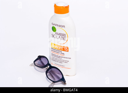 Una bottiglia di crema solare e un paio di occhiali da sole isolato su uno sfondo bianco Foto Stock