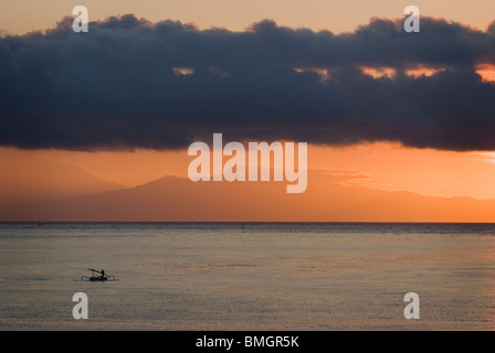 Come il sole sorge su Amed, Bali, pescatori nelle loro piccole imbarcazioni chiamato jukung rientro a riva a sbarcare le loro catture di giorno in giorno. Foto Stock