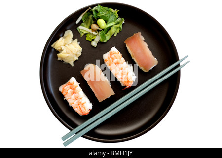 Selezione di stile Giapponese pesce crudo e il riso sushi servita su una piastra nera con bacchette isolata contro uno sfondo bianco con un tracciato di ritaglio Foto Stock