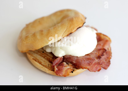 Uovo affogato e pancetta su un bagel Foto Stock