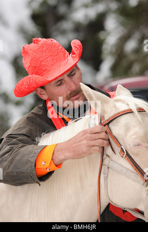 Close-up di bello cowboy hunter getting white horse pronto per l'equitazione Foto Stock