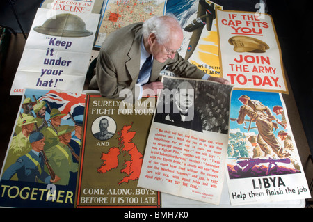 Roy Butler un esperto di Militaria per la BBC di 'Antiquariato Road Show" ispeziona la Prima Guerra Mondiale e la guerra mondiale 2 poster. Foto Stock