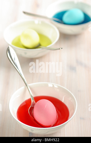 Le uova di pasqua essendo tinto in diverse bocce delle colorate dye Foto Stock