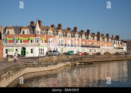 Il lungomare, il mare a parete, scivolo e pennelli di pietra a Swanage in la mattina di sole Foto Stock