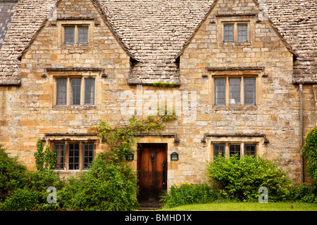 Un tipico Cotswold stone country house con luci con piombo, bifore, gable fronteggiata finestre dormer e un di legno porta anteriore Foto Stock