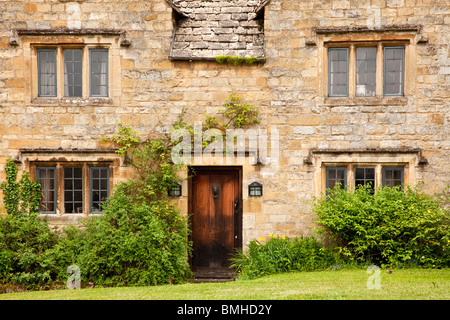 Un tipico tradizionale antica pietra di Cotswold village country house con luci con piombo e bifore in legno e lo sportello anteriore. Foto Stock