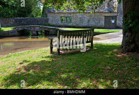 Panca in legno che si affaccia sulla Ford nel grazioso villaggio Costwold di Shilton, Oxfordshire, England, Regno Unito Foto Stock