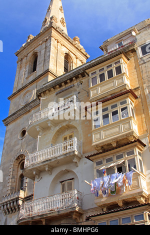 La torre di San Paolo Cattedrale Anglicana di La Valletta, Malta. Adiacente è una tradizionale casa Maltese con balconi chiusi Foto Stock