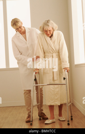 Lavoratore Healthcare aiuta una donna a piedi con un viandante Foto Stock