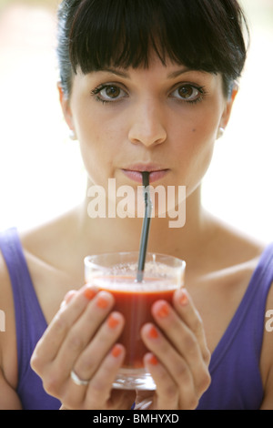 Giovane donna di bere succo di pomodoro. Modello rilasciato Foto Stock