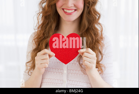 Donna che mantiene un cuore rosso Foto Stock