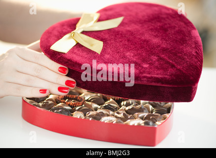 Apertura a mano in velluto a forma di cuore ad una scatola di cioccolatini Foto Stock