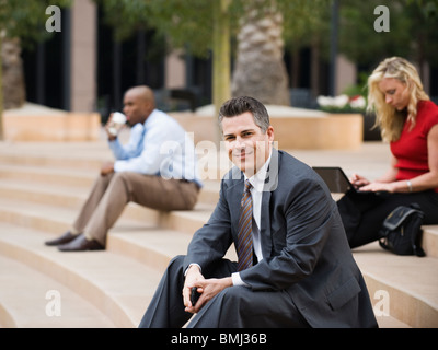 La gente di affari seduti sui gradini esterni Foto Stock