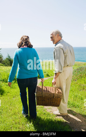 Coppia portando un cestino picnic per la spiaggia Foto Stock