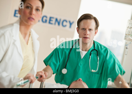 I lavoratori del settore sanitario spingendo barella in sala di emergenza Foto Stock