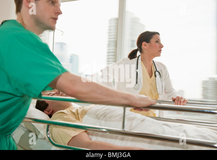 I lavoratori del settore sanitario spingendo barella in sala di emergenza Foto Stock