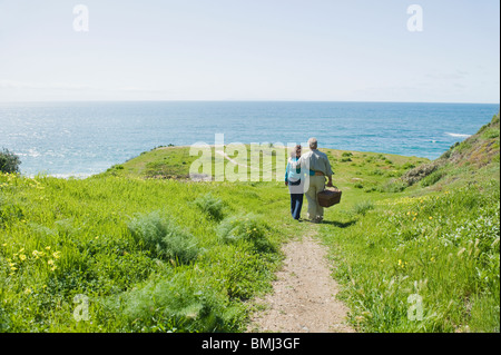 Coppia portando un cestino picnic per la spiaggia Foto Stock