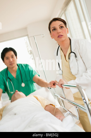 I lavoratori del settore sanitario spingendo barella in sala di emergenza Foto Stock