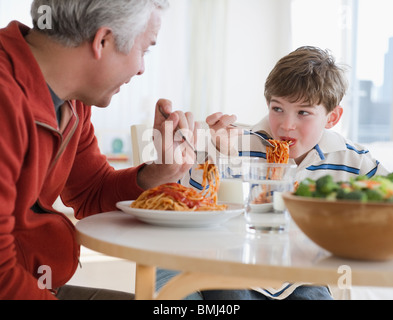 Padre e figlio mangiare spaghetti Foto Stock