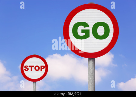 Round cartelli con GO e STOP sul loro contro un blu cielo nuvoloso. Foto Stock