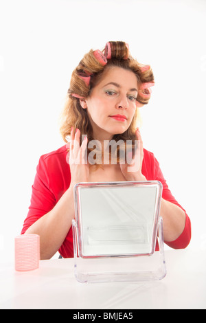 Donna di mezza età in rosso con i capelli rulli - isolato su bianco Foto Stock