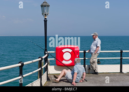 Due maschi uomini adulti di pesca da una lampada posta e stazione lifebelt su un angolo del molo di Worthing SUSSEX REGNO UNITO Foto Stock