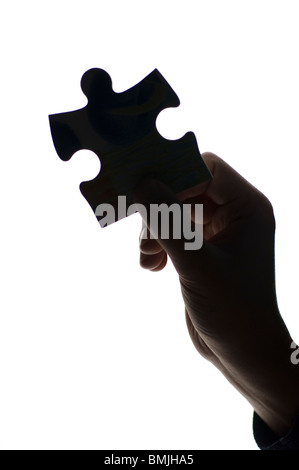 Silhouette della mano umana tenendo pezzo del puzzle, close-up Foto Stock