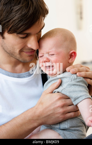 Padre holding Gridando bambino Foto Stock