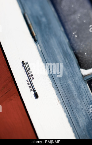 Termometro da parete per esterni con neve e caduta di temperatura in gradi  Fahrenheit o Centigradi. Recinzione di legno e sfondo di albero . Primo  piano del termometro bianco Foto stock - Alamy