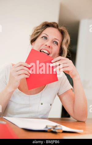 Donna leccare sulla busta rossa Foto Stock