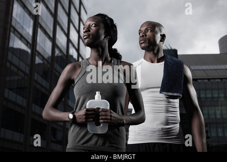 Athletic uomo e donna vestita di sportswear backgrounded dai moderni edifici della città Foto Stock