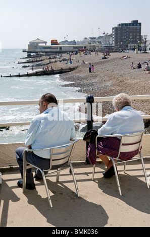 Una coppia di anziani e dei cittadini anziani seduti su Worthing pier affacciato sulla spiaggia di ciottoli sulla costa Sud a SUSSEX REGNO UNITO Foto Stock