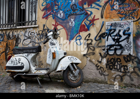 Un scooter Vespa completamente ricoperta di graffitti, davanti a una parete con Graffitti troppo, Roma, Italia Foto Stock