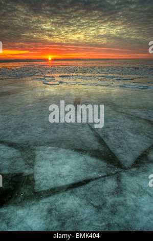 Sunrise attraverso un congelato il lago di acqua dolce nel Michigan, Stati Uniti, America del nord con lo spostamento degli strati di ghiaccio sotto la superficie Foto Stock