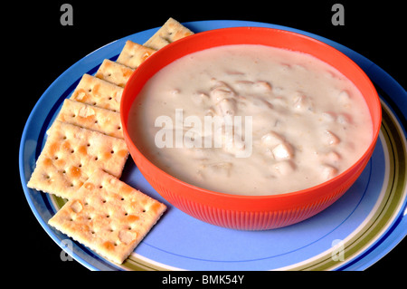 Ciotola di zuppa di vongole con cracker isolate su nero Foto Stock