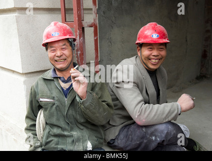 Due lavoratori edili di prendere una pausa sigaretta, Shanghai, Cina Foto Stock