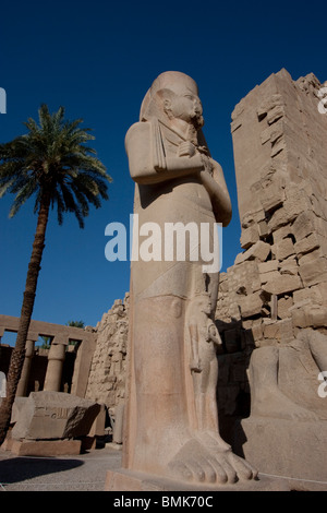 Statua colossale di Ramses II con una piccola figura della sua Regina Nefertari in piedi tra i suoi piedi Foto Stock