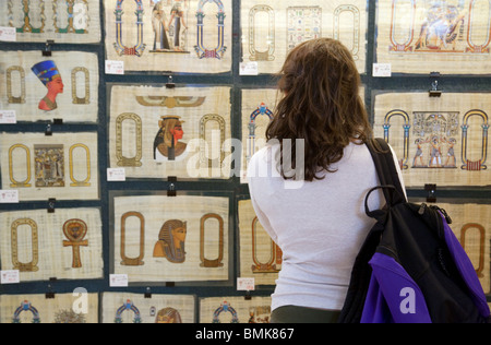 Un turista occidentale guardando dipinti moderni su papiro in un papiro store, Il Cairo in Egitto Foto Stock