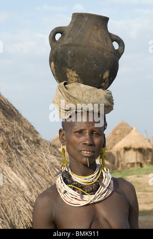 Etiopia: inferiore Omo river basin, Karo villaggio di Duss, donna con perline collane che porta una pentola di cottura sul suo capo Foto Stock