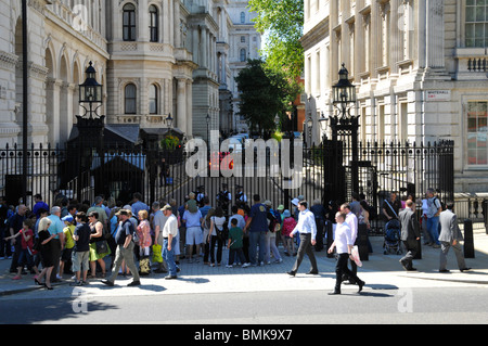 Turisti sul lato di Whitehall di Downing Street di fronte in acciaio cancelli di sicurezza comandati da Metropolitan poliziotti Londra Inghilterra REGNO UNITO Foto Stock