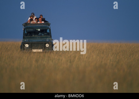 Africa, Kenia Masai Mara Game Reserve, turisti guardare da aprire Safari carrello in mattinata game drive sulla savana Foto Stock