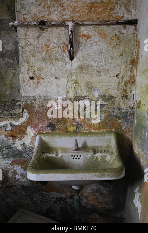 Bagno abbandonati e lavabo in carcere militare della fortezza de La Mola, Menorca, Spagna. Le alghe sui muri cadenti Foto Stock