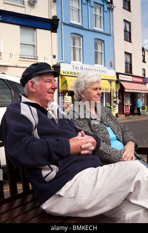 Regno Unito, Inghilterra, Devon, Brixham Harbour, lungomare, coppia di anziani rilassante al sole sulla banchina Foto Stock