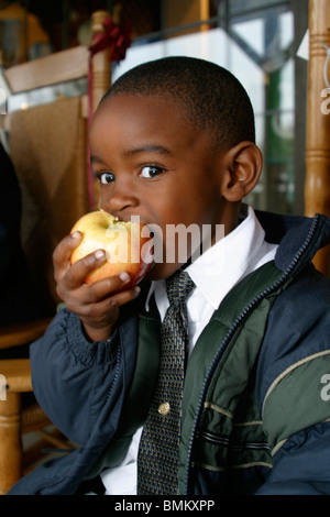 Da 5 a 7 anni di eta' African American boy eating Apple nella parte anteriore del Cracker Barrel negozio e ristorante in Florida MR © Myrleen Pearson Foto Stock