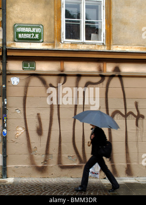 Pedone passato a piedi di graffiti su un edificio a Ljubljana, Slovenia Foto Stock